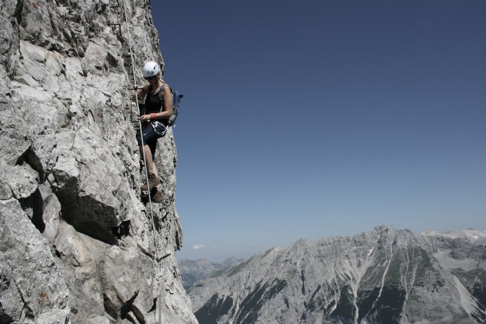 Frau klettert am Innsbrucker Klettersteig nach oben. 